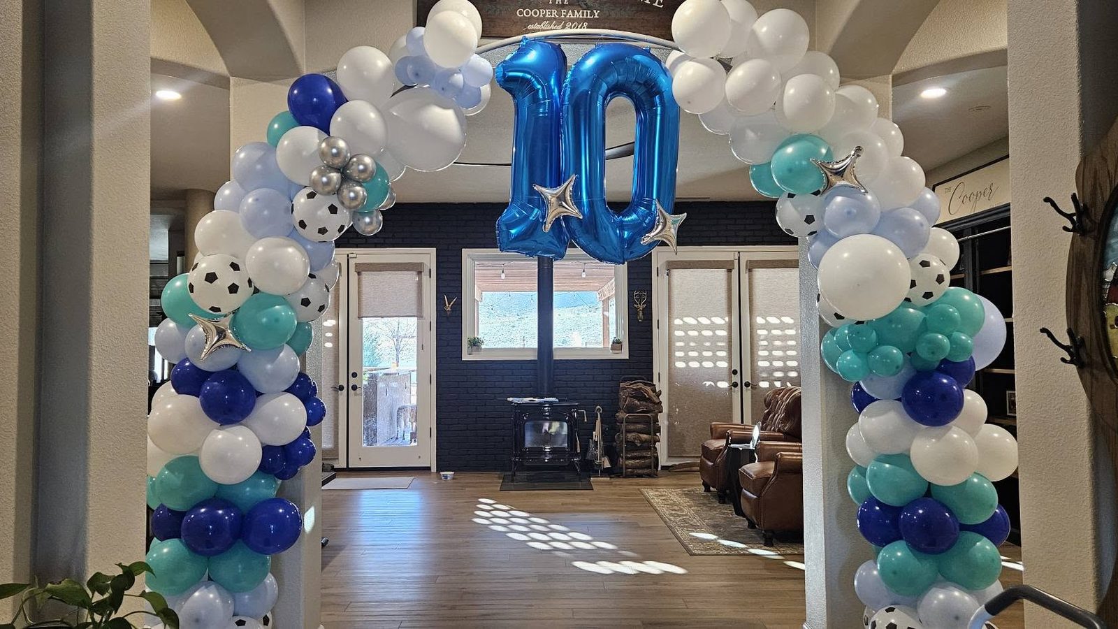 A navy, teal, and white balloon arch over a doorway with a large foil number ten at the crown